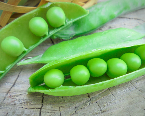 新鮮な甘い緑のエンドウ豆のオープンポッドは木製の表面にあります - 写真・画像
