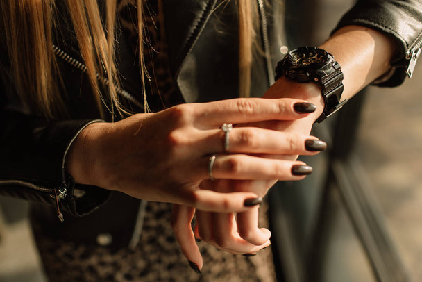 Black watch with golden arrows on a woman's hand. Fashion watches in a modern style - Foto, afbeelding