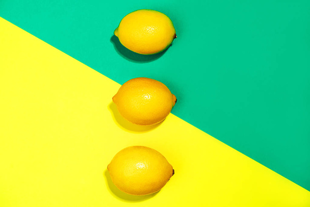 Creative pattern made of lemons on bright yellow and trendy green blue background. - Foto, Imagen