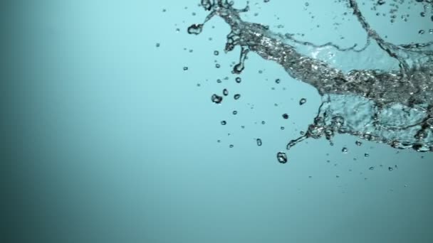 Víz fröccsent a kék háttér, szuper lassított felvétel. Fényképezte: nagy sebességű mozi kamera. - Felvétel, videó
