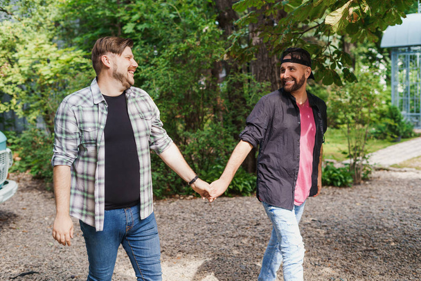 Two adult gay men walking, holding each others hands - Фото, зображення
