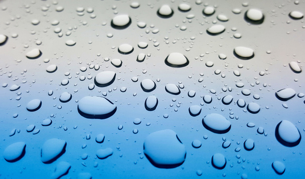 Splashes of raindrops on a car windshield after a storm. Angled point of view for depth of field and selective focus. - Photo, Image