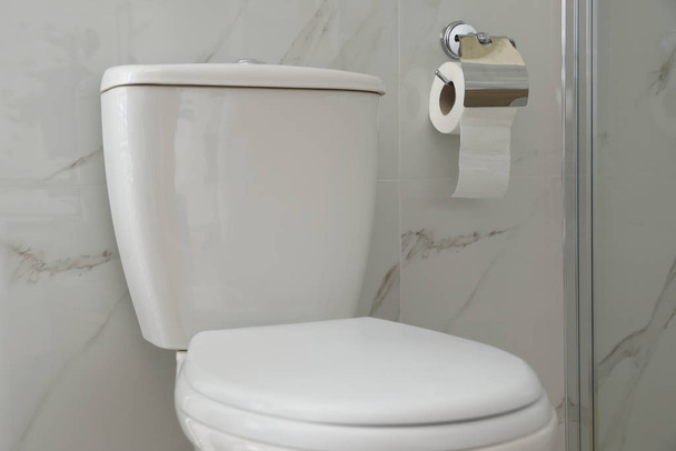 Modern toilet and holder with paper roll indoors - Φωτογραφία, εικόνα
