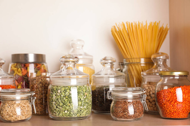 Glass jars with different types of groats on wooden shelf - Foto, immagini