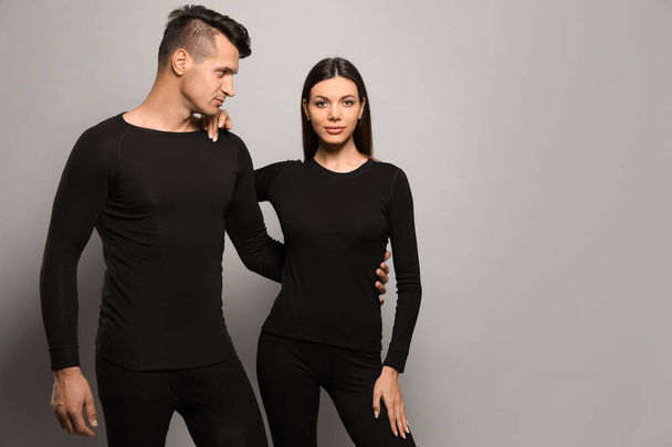 Couple wearing thermal underwear on grey background. Space for text - Φωτογραφία, εικόνα