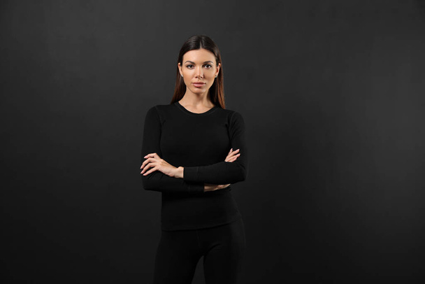 Woman wearing thermal underwear on black background - Photo, Image
