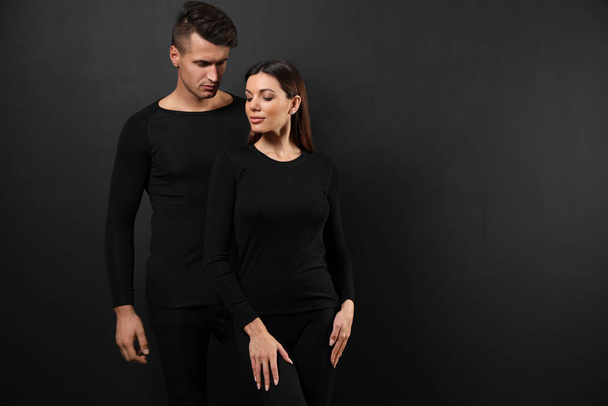 Couple wearing thermal underwear on black background. Space for text - Foto, Bild