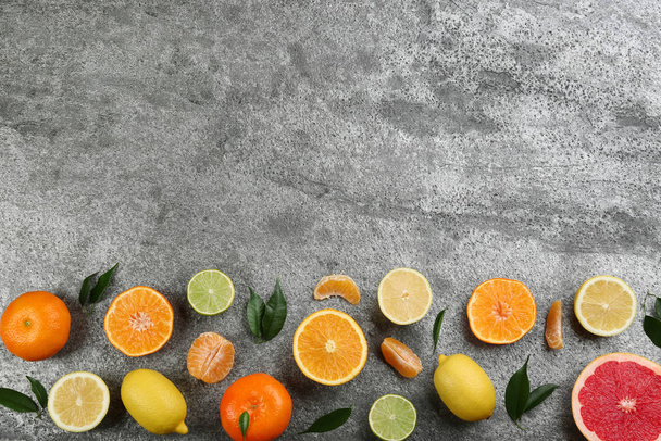 Flat lay composition with tangerines and different citrus fruits on grey background. Space for text - Fotó, kép