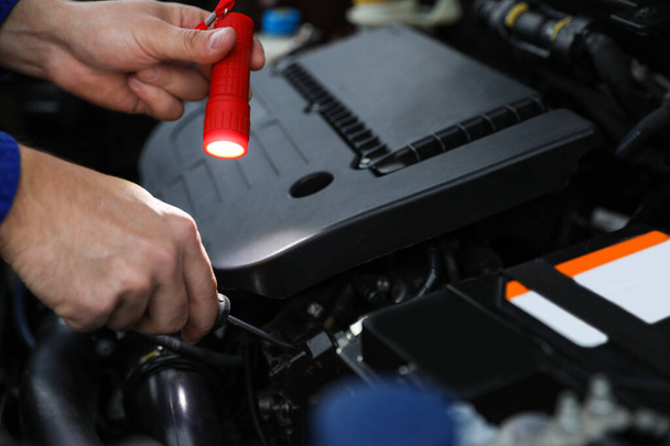 Mechanic with flashlight fixing car, close seup view
 - Фото, изображение