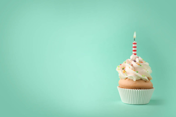 Delicious birthday cupcake with candle on light green background - Foto, Bild