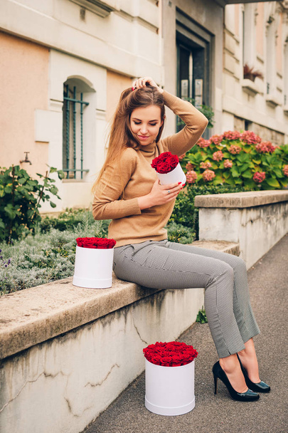 На відкритому повітрі портрет красивої молодої жінки врятував подарункові коробки з червоними трояндами
 - Фото, зображення