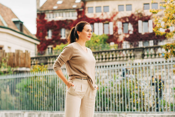 Outdoor portrait of beautiful woman posing on the city street, wearing beige pullover - Photo, Image