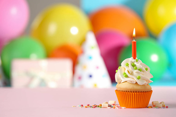 Verjaardag cupcake met kaars op roze tafel tegen wazig backg - Foto, afbeelding