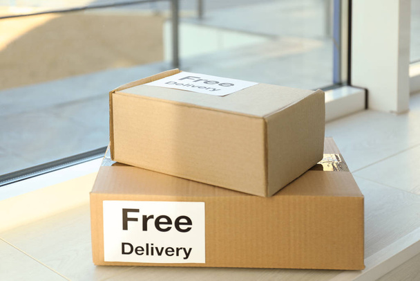 Parcels with sticker Free Delivery on window sill. Courier service - Zdjęcie, obraz