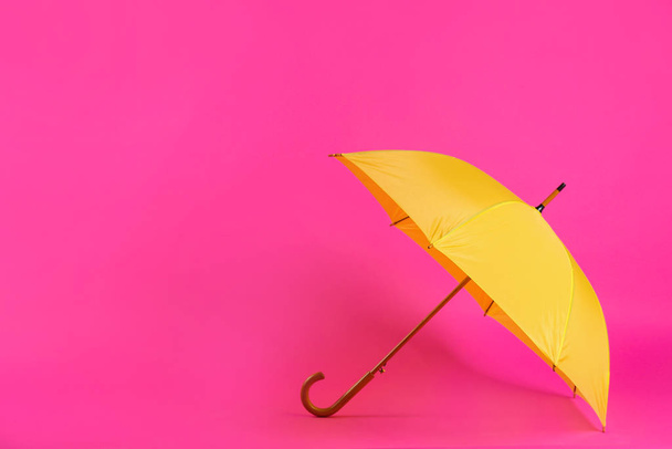 Beautiful yellow umbrella on pink background. Space for text - Фото, зображення