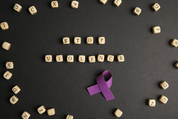 Purple ribbon and phrase STOP VIOLENCE made of wooden cubes on black background, flat lay - Foto, imagen