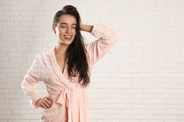 Young woman in bathrobe with wet hair near white brick wall. Spa - Foto, Imagem
