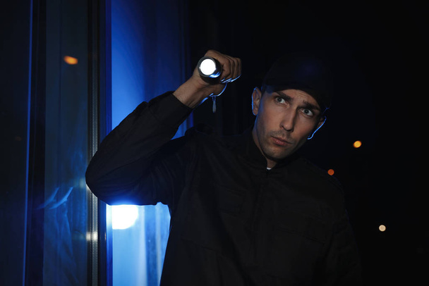 Male security guard with flashlight in dark corridor - Foto, Imagen