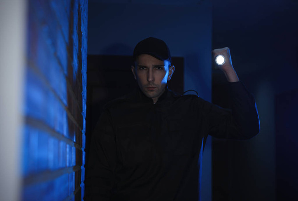 Чоловічий охоронець з ліхтариком в темному коридорі
 - Фото, зображення