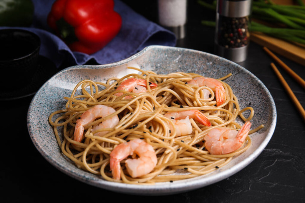 Tasty buckwheat noodles with shrimps served on black table - Fotografie, Obrázek