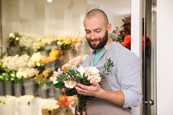 Professional florist with bouquet of fresh flowers in shop - Фото, изображение