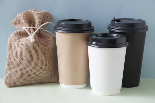 Tasse en papier de café avec sac de toile de jute sur fond coloré un
 - Photo, image
