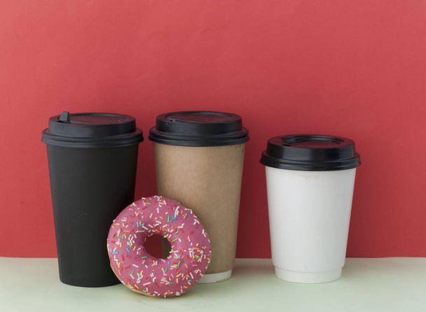круглый красный глазурованный пончик и бумажная чашка с кофе
 - Фото, изображение