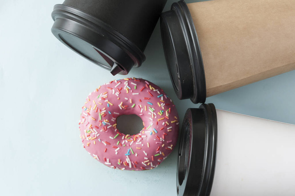 ronde rode geglazuurde donut en papieren beker met koffie - Foto, afbeelding