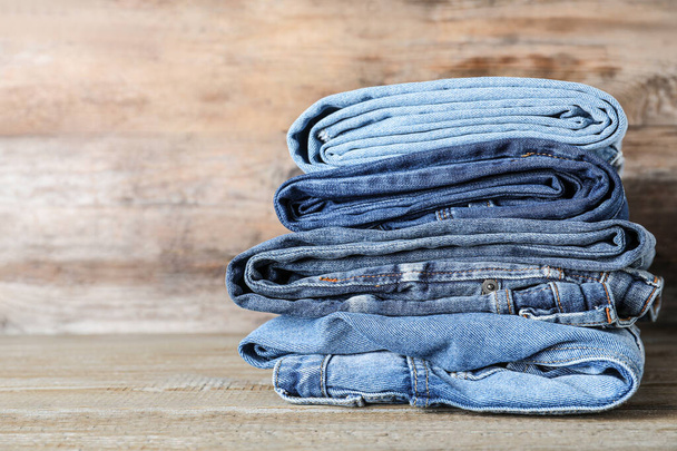 Stack of different jeans on wooden table. Space for text - Fotografie, Obrázek