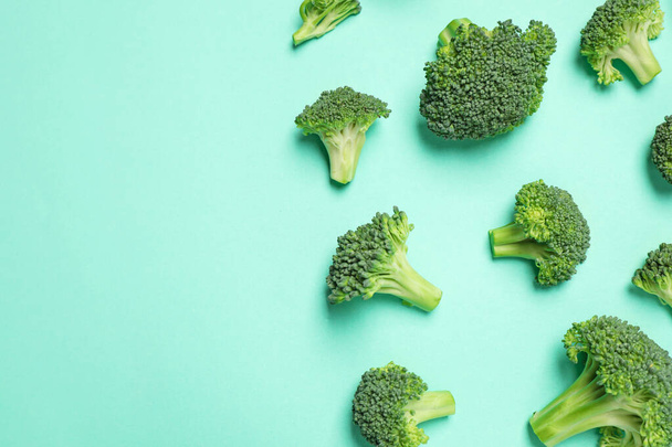 Fresh tasty broccoli on turquoise background, flat lay. Space for text - Foto, afbeelding