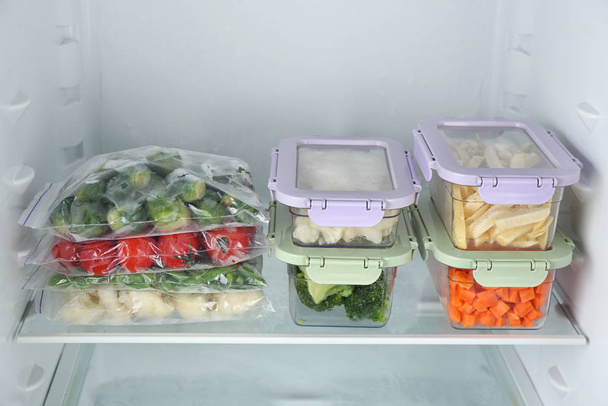 Plastic bags and containers with different frozen vegetables in refrigerator - Photo, Image