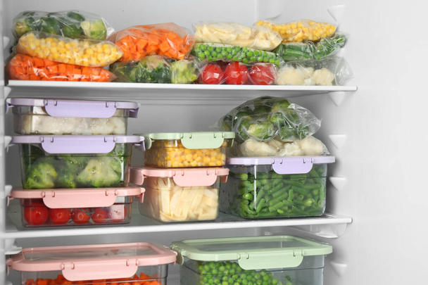 Bolsas de plástico y recipientes con diferentes verduras congeladas en nevera - Foto, imagen