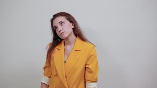 mooie jonge vrouw in geel jasje houden hand op wang, op zoek verveeld - Video