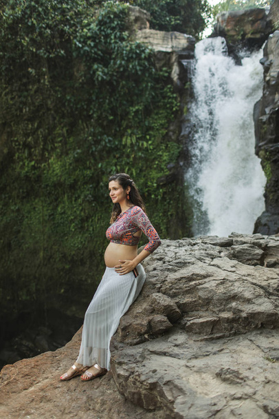 Mladá autentická těhotná žena poblíž úžasného kaskádového vodopádu. N - Fotografie, Obrázek