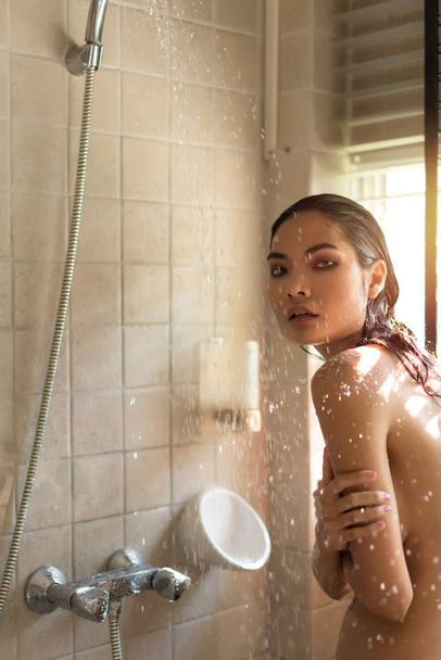 mujer sorprendida asomándose de disfrutar de la ducha con desnudo debajo de wate
 - Foto, Imagen