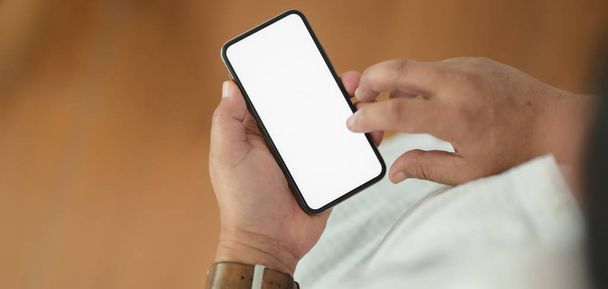 Close-up view of man holding his smartphone with blurred office  - Foto, Imagen