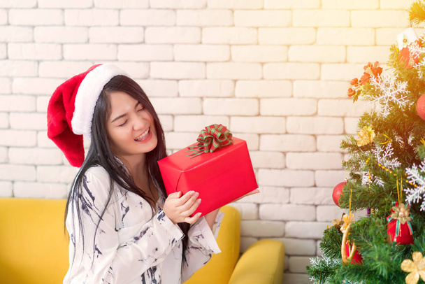 Boldog nő visel Mikulás kalap kezében egy ajándékot karácsonykor és N - Fotó, kép