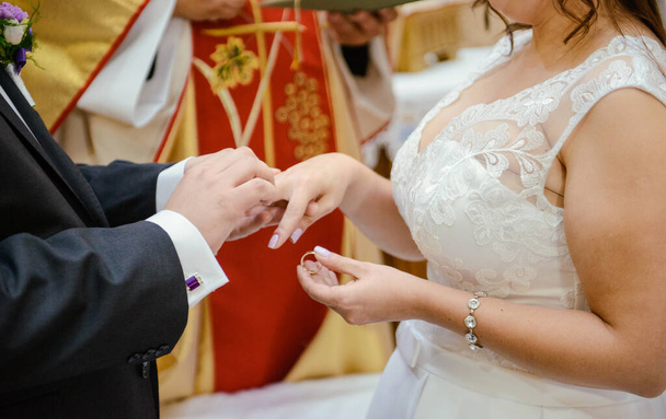 Braut und Bräutigam während der Trauung legen Ehering an - Foto, Bild