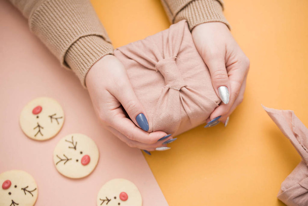 Presente em mãos femininas com uma bela manicura. Presente em embalagem ecológica - Furoshiki
. - Foto, Imagem