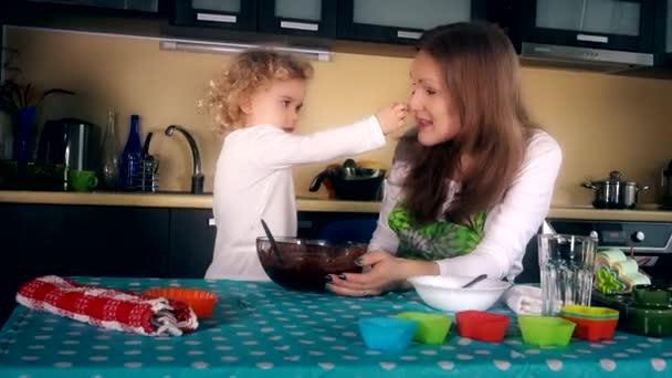 Mother and daughter put chocolate dough on nose. Happy family girls playing - Footage, Video