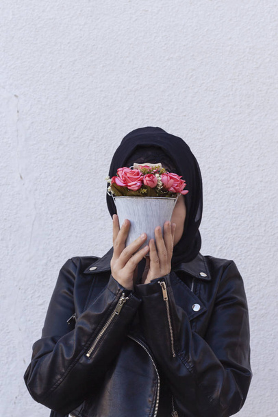 Piękna środkowo-wschodnia dziewczyna trzyma dekoracyjny kosz pełen kwiatów. Cute arabski muzułmanin kobieta otrzymała unikalny kwiat bukiet jako prezent na urodziny - Zdjęcie, obraz