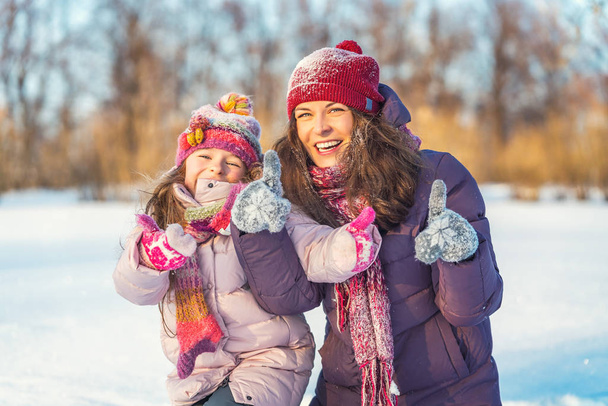 Positieve moeder en dochter spelen in winterpark - Foto, afbeelding