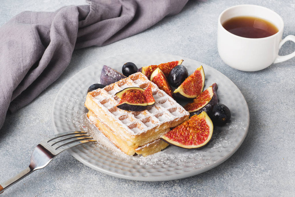 Traditional Belgian waffles with powdered sugar grapes and figs. Cozy homemade Breakfast. Gray concrete background. Copy space. - Valokuva, kuva
