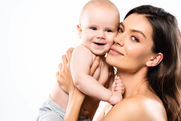 portrait of attractive nude mother holding cheerful baby, isolated on white - Foto, Imagen