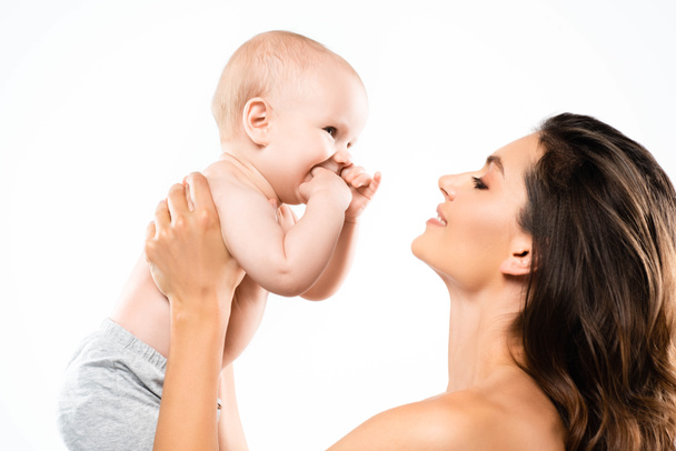 portrait of nude happy mother looking at baby, isolated on white - Фото, зображення
