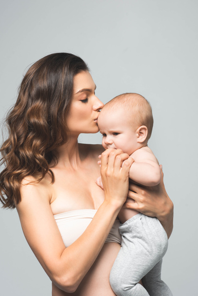 魅力的な母親の肖像画灰色で隔離された赤ん坊の少年にキス - 写真・画像