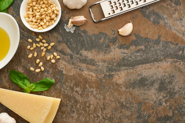 top view of pesto sauce ingredients and grater on stone surface - Foto, afbeelding