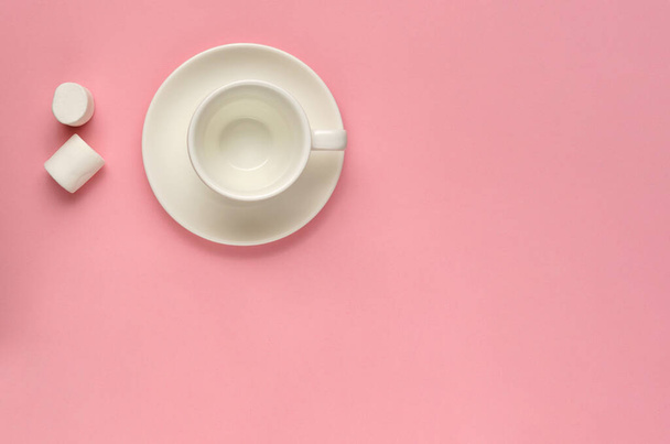 Clean empty white coffee cup with saucer and two marshmallows on pink background. Minimal template for feminine blog, social media, networks. Pink mood concept. Flat lay. Copy space - Фото, изображение
