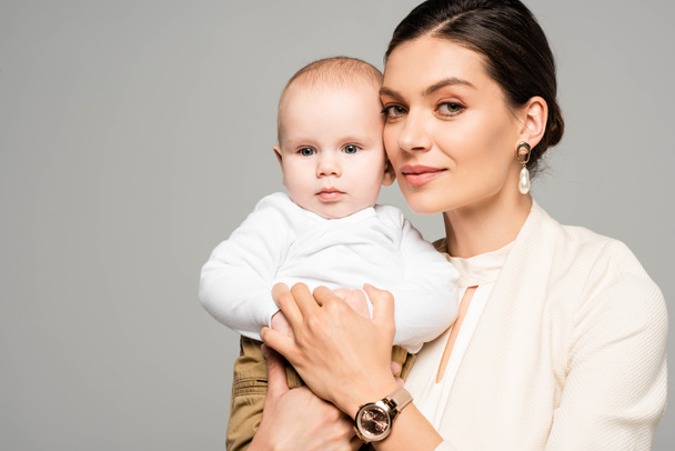 smiling businesswoman with little baby on hands, isolated on grey - Valokuva, kuva