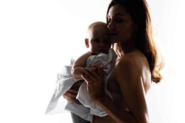 sylwetka pięknej matki trzymając chłopca na rękach, odizolowany na białym - Zdjęcie, obraz